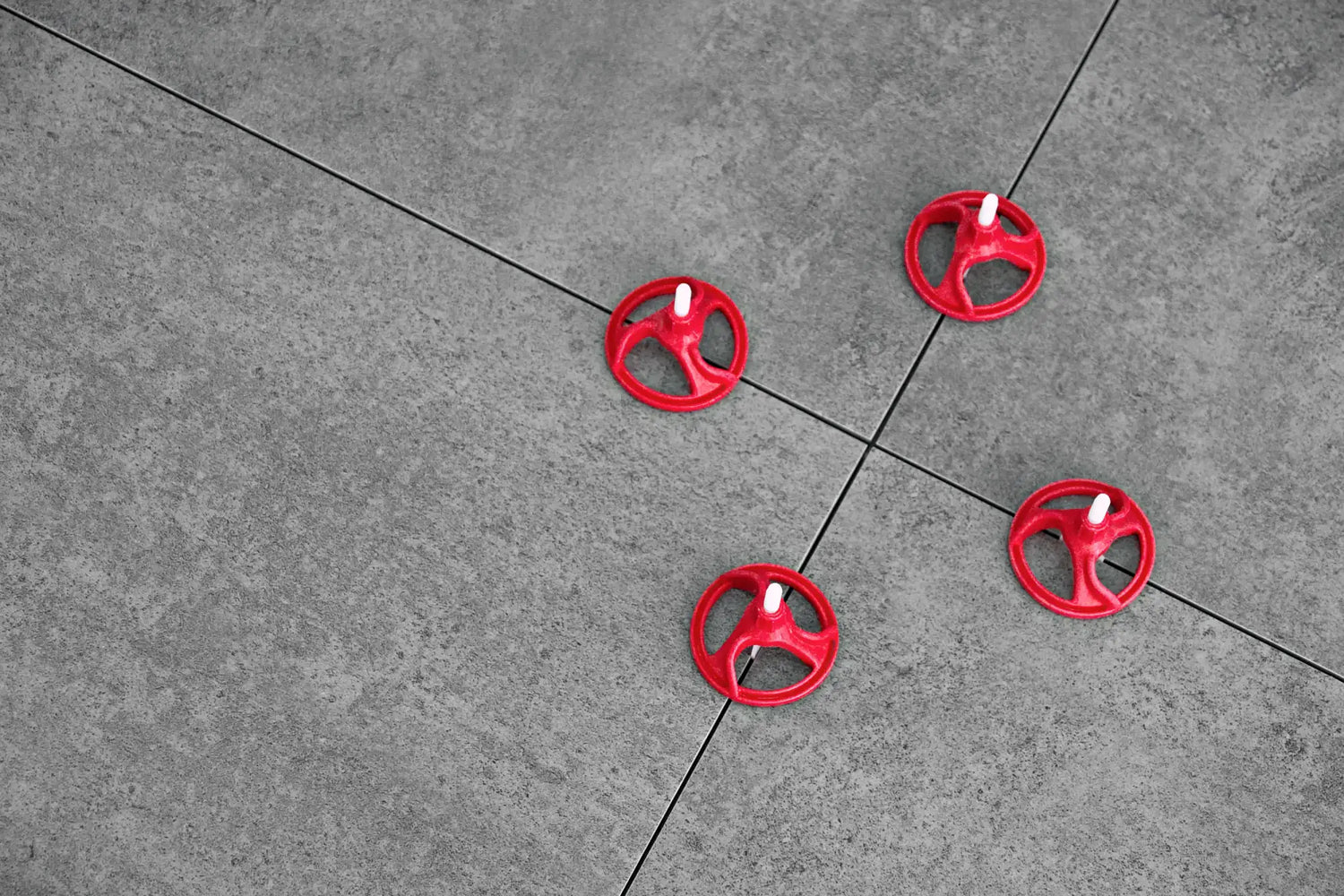 Rote Kunststoff-Fliesenkreuze mit weißen zentralen Stiften.